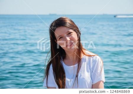 Young woman relaxing by the ocean on a sunny day. Happy summer days, travel and vacation concept 124848869