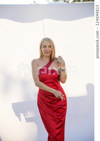 Beautiful blonde woman in red dress smiling with blue eyes Beautiful blonde woman in red dress smiling with blue eyes 124849815