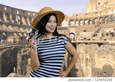 Young asian tourist woman is holding vintage photo camera. Rome Coliseum background. Young asian tourist woman is holding vintage photo camera. Rome Coliseum background. 124850206