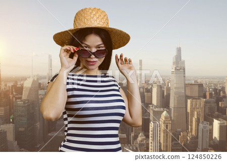 Portrait of a young sexy asian woman in straw hat and sunglasses. Urban cityscape background. 124850226