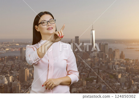 Asian businesswoman is using an invisible virtual screen. Urban evening cityscape background. 124850302
