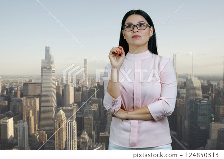Young asian woman standing outdoors and thinking. Urban city scape background. 124850313