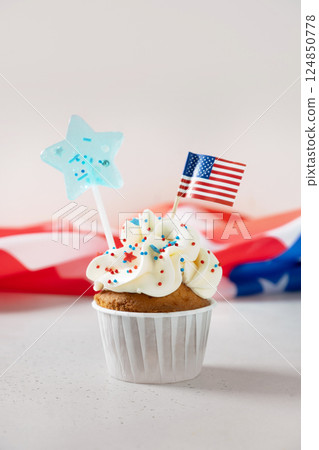 Traditional American vanilla sweet cupcake with festive decorations and USA flag on white background. Vertical format. Food and dessert for Patriotic Independence Day 4th of July. 124850778