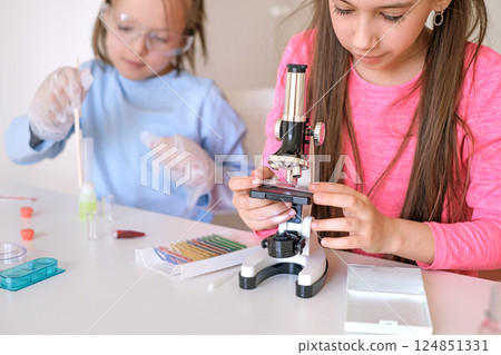 Children look at the structure of the particles of objects under a microscope at school in the classroom Children look at the structure of the particles of objects under a microscope at school in the classroom 124851331