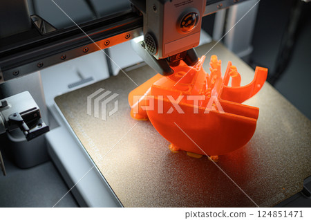 3D Printer Creating Orange Plastic Object on Platform 3D Printer Creating Orange Plastic Object on Platform 124851471