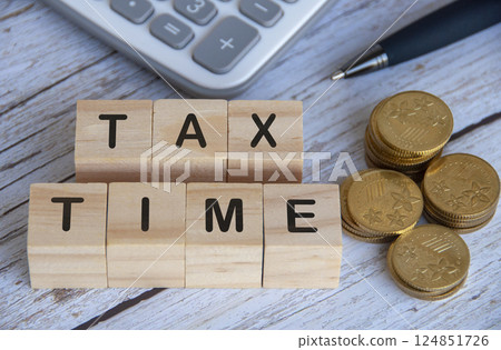 Top view of Tax Time text on wooden cubes surrounded by gold coins and calculator 124851726
