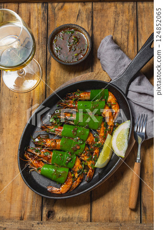 Delicious shrimp with a glass of white wine at a rustic dining table 124852065