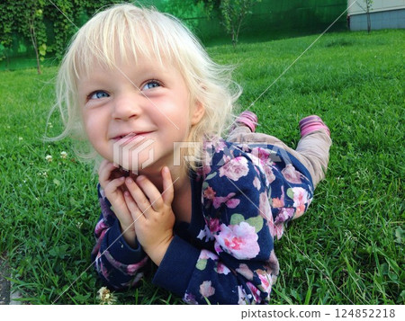 Joyful Child Lying on Grass with Dreamy Expression 124852218