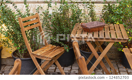 Empty bread bin street cafe without people on wooden table and chair with cutlery, raindrops 124852703