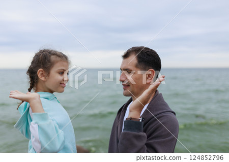 Clapping palms of happy father and daughter in blur against sea 124852796