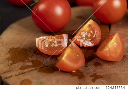 red ripe tomatoes sliced on a walnut board, several ripe red tomatoes during slicing for cooking, side view 124853534