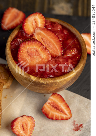 grated ripe strawberries in a wooden bowl, making a sweet dessert of strawberries, mashed without adding sugar 124853544