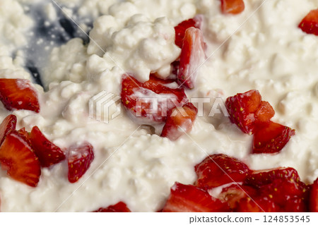 white sour-milk cottage cheese with ripe sweet strawberries cut into pieces, close up white sour-milk cottage cheese with ripe sweet strawberries cut into pieces, close up 124853545