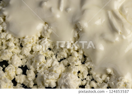 white cottage cheese with sour cream, sprinkled with liquid sour cream, lumps of freshly made fermented milk , close up white cottage cheese with sour cream, sprinkled with liquid sour cream, lumps of freshly made fermented milk , close up 124853587