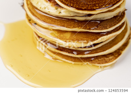 a tower of small milk pancakes on a ceramic bowl with natural yellow bee honey, close up 124853594
