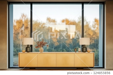 Elegant interior design featuring a modern sideboard with lamps and a view of autumn foliage 124853856