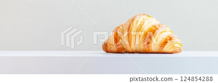 Golden brown croissant with flaky layers levitating slightly above a white surface, creating a visually appealing image with a minimalist aesthetic, ideal for food and bakery related projects 124854288