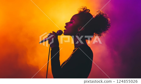 Silhouette of young female singer passionately performing live on stage with colorful lights and microphone, creating a vibrant and energetic atmosphere Silhouette of young female singer passionately performing live on stage with colorful lights and microphone, creating a vibrant and energetic atmosphere 124855026