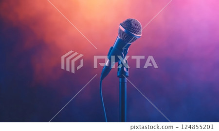 Professional microphone stands ready on stage, bathed in vibrant orange and purple hues, anticipating a performance filled with music and sound 124855201