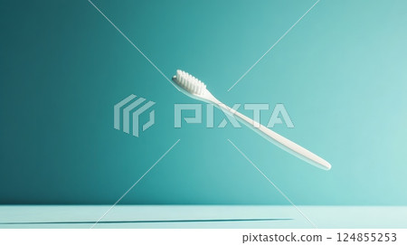 Single white toothbrush floats in the air against a vibrant turquoise backdrop, symbolizing good oral hygiene practices and the importance of dental care 124855253