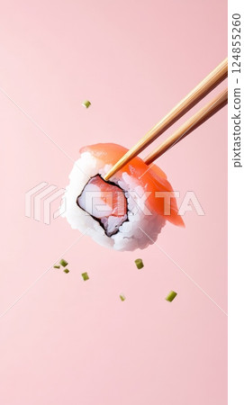 Wooden chopsticks are holding a levitating salmon sushi roll with rice and chives falling against a vibrant pink background, creating a dynamic and appetizing culinary scene 124855260