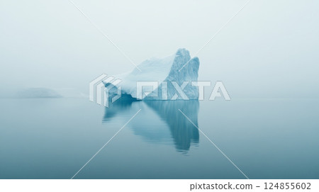 Large iceberg floating on calm water with another smaller iceberg in the background and heavy fog creating a serene and minimalist landscape 124855602