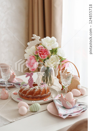 Table setting with traditional easter cakes with icing decorated with gingerbread cookies in shape of rabbits on white wooden table Table setting with traditional easter cakes with icing decorated with gingerbread cookies in shape of rabbits on white wooden table 124855718