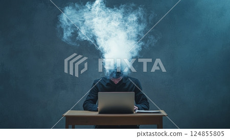 Smoke is coming out of the head of a stressed businessman working on his laptop at a wooden desk, representing an information overload or a burnout 124855805