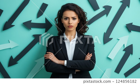 Businesswoman standing with arms crossed and looking serious against a turquoise background, facing arrows pointing in various directions, symbolizing choice and fear of better options 124856182