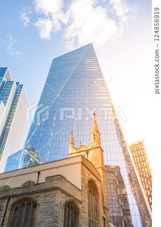 St Andrew Undershaft Church stands in contrast to the sleek skyscrapers of London's financial district. The sunlight reflects off the glass buildings surrounding this historic site. St Andrew Undershaft Church stands in contrast to the sleek skyscrapers of London's financial district. The sunlight reflects off the glass buildings surrounding this historic site. 124856919