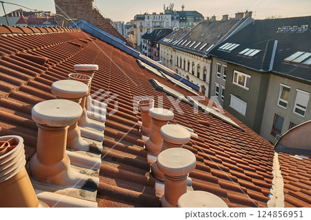 Tiled city building roofs with air vent pipes 124856951