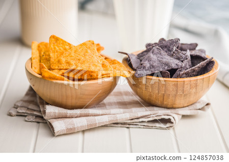 Dark and yellow nachos chips in bowl on white table. Dark and yellow nachos chips in bowl on white table. 124857038