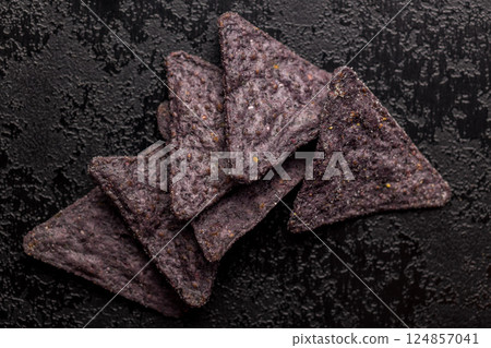 Dark nachos chips on black table. Top view. Dark nachos chips on black table. Top view. 124857041