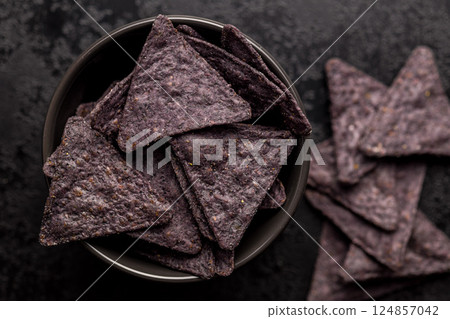 Dark nachos chips in bowl on black table. Top view. Dark nachos chips in bowl on black table. Top view. 124857042