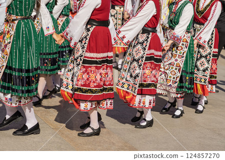 Women in traditional Balkan dresses perform group folk Bulgarian dance in sunlight. Traditional dance. Women in Bulgarian folk costumes dancing at outdoor festival Women in traditional Balkan dresses perform group folk Bulgarian dance in sunlight. Traditional dance. Women in Bulgarian folk costumes dancing at outdoor festival 124857270