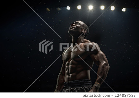An African boxer raised his head in prayer after winning a fight. View from below. An African boxer celebrates his victory with a grateful prayer to the God. 124857552