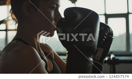 Young mixed race woman in boxing gym. Self defense workout concept. Embracing self-defense, she exudes strength and focus. 124857574