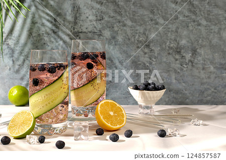 Refreshing summer drink recipe, Cold homemade lemonade or cocktail with chia seeds, blueberries, lemon, cucumber and lime on a sunny table, Detox diet and summer party concept. Restaurant menu 124857587