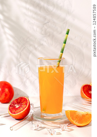 Modern still life with citrus fruits, orange juice, oranges and blood orange on elegant kitchen table with long hard shadows. Minimal detox diet concept, summer vitamin drinks, selective focus 124857589