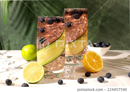 Cold homemade lemonade or cocktail with chia seeds, blueberries, lemon, cucumber and lime on a sunny table, Detox diet and summer party concept. Refreshing summer drink recipe, restaurant menu 124857590