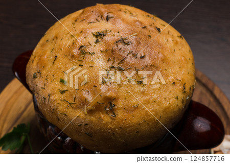 A pot with baked meat and a bread lid on a wooden A pot with baked meat and a bread lid on a wooden 124857716