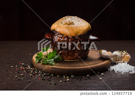 A pot with baked meat and a bread lid on a wooden A pot with baked meat and a bread lid on a wooden 124857719