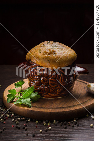 A pot with baked meat and a bread lid on a wooden 124857720