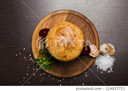 A pot with baked meat and a bread lid on a wooden 124857721