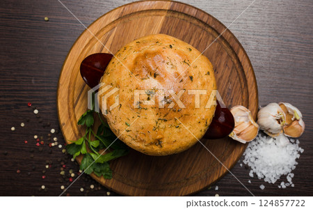 A pot with baked meat and a bread lid on a wooden A pot with baked meat and a bread lid on a wooden 124857722