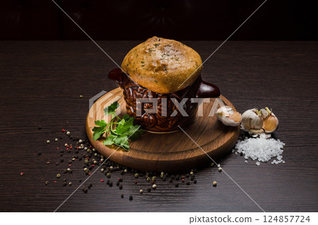 A pot with baked meat and a bread lid on a wooden A pot with baked meat and a bread lid on a wooden 124857724