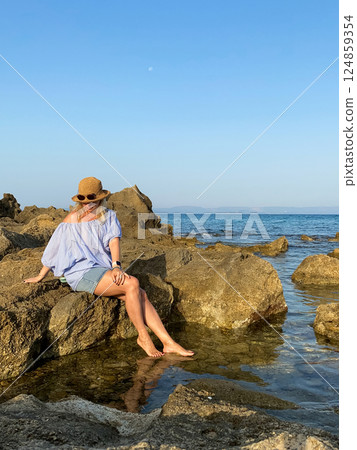 Woman relaxing on rocks by the sea 124859354