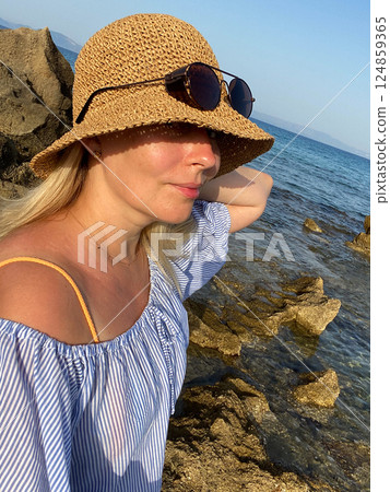 Woman relaxing on rocks by the sea 124859365
