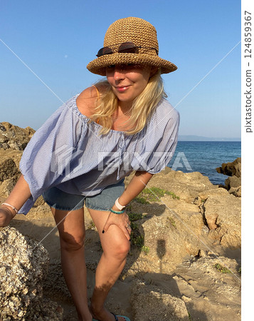 Woman relaxing on rocks by the sea Woman relaxing on rocks by the sea 124859367