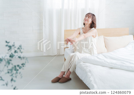 Middle-aged woman stretching in bed in the morning Middle-aged woman stretching in bed in the morning 124860079